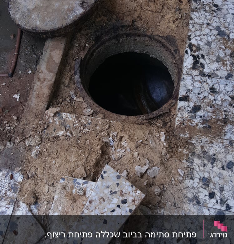 פתח ביוב פתוח עם מכסה בטון מונח בצד